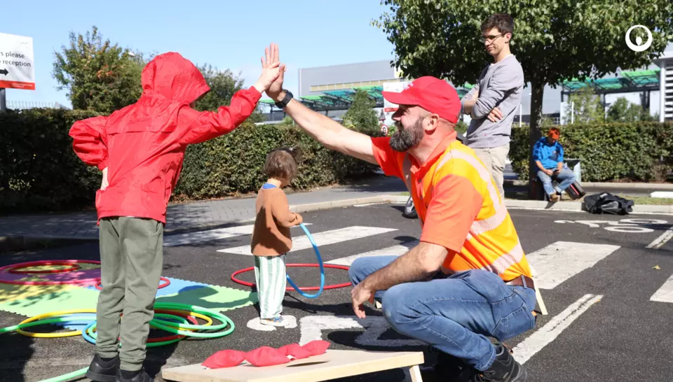 a photo of a child high-fiving a veolia employee in orange high-visability clothing