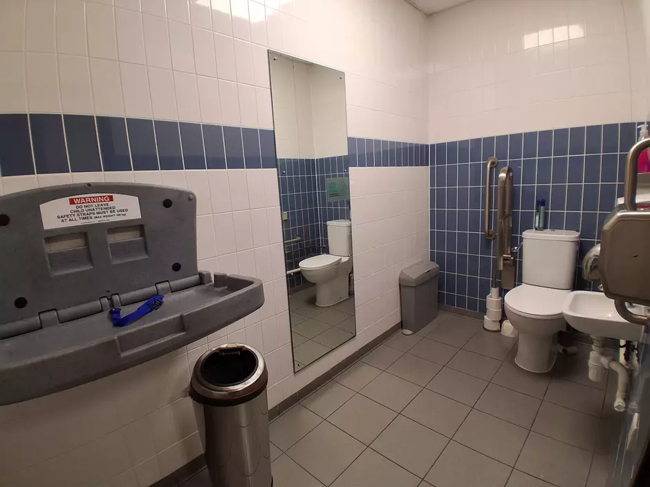 A photo of the accessible toilet at Southwark Recycling Discovery Centre. There is a large bathroom with baby changing table, toilet and sink. 